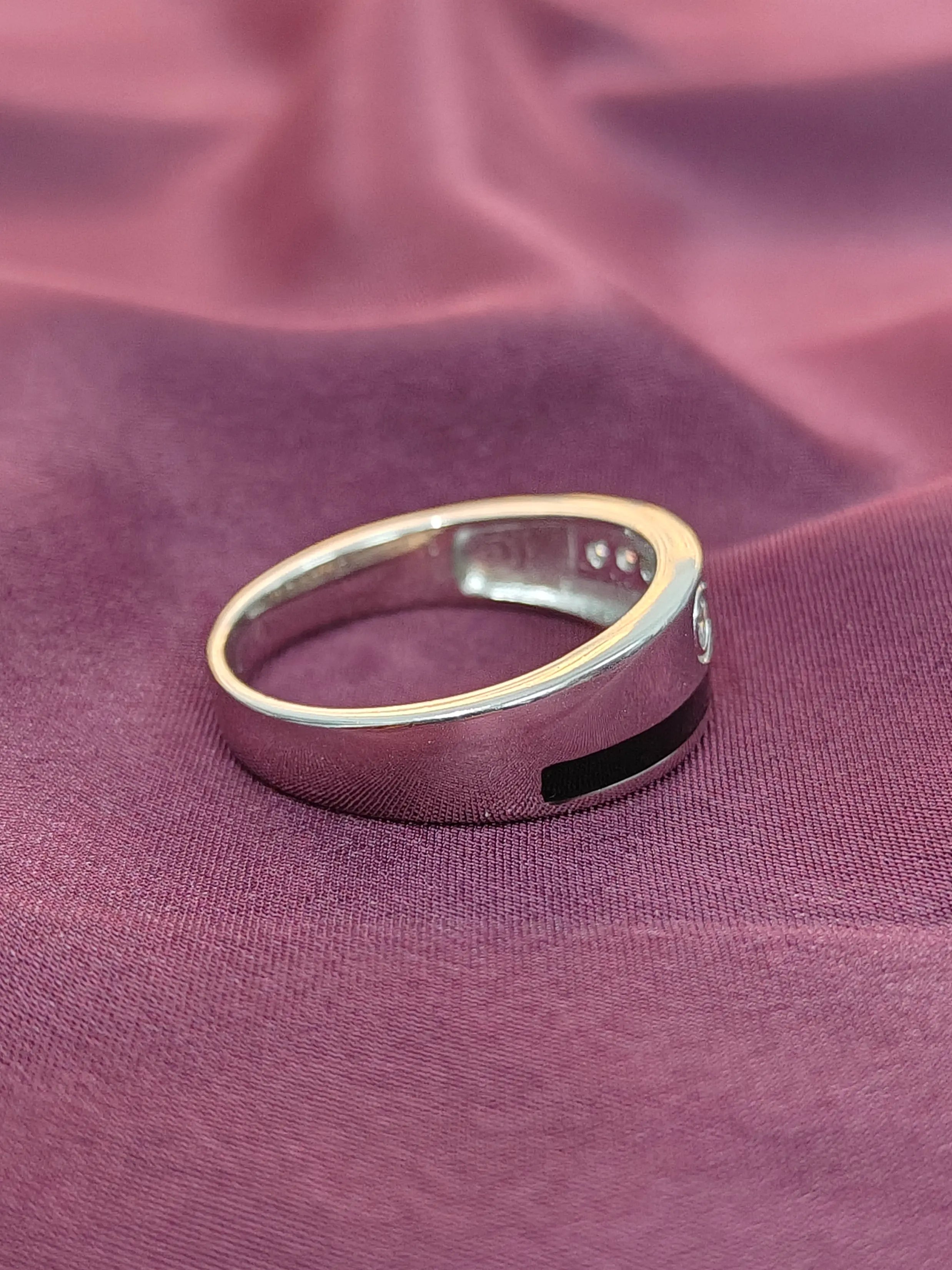 Silver ring with a black band on a purple fabric background